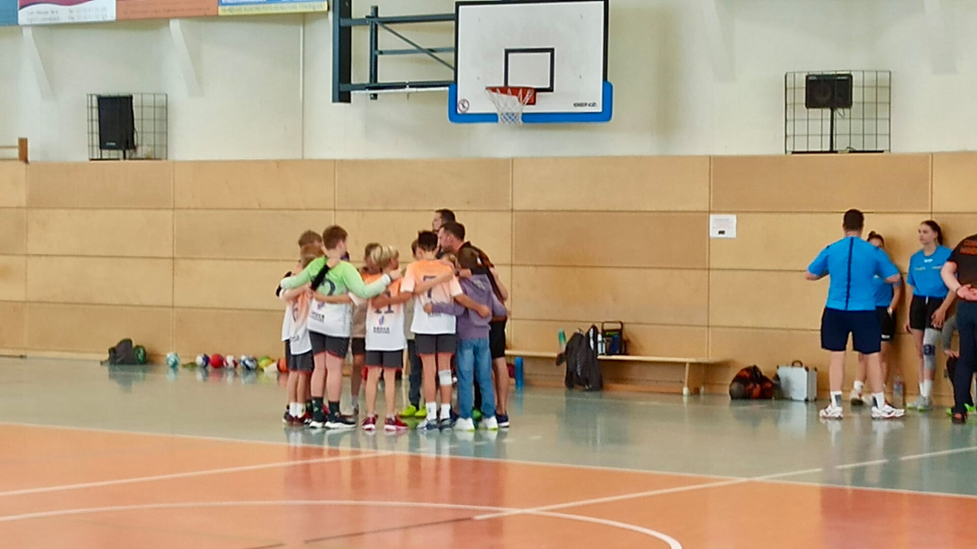 Eine Gruppe junger Kinder, die Minis der HSG Coswig, stehen mit ihren Trainern in einer Sporthalle und schauen in die Kamera.