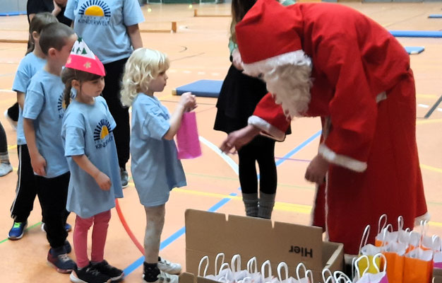 Der Weihnachtsmann verteilt Geschenke an aufgeregte Kinder der Coswiger Handballspielgemeinschaft in einer Sporthalle.