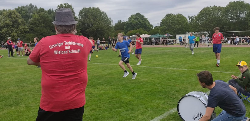 Handball-Torhütercamp der Coswiger Handballspielgemeinschaft im Freien auf einem grünen Sportplatz mit Jugendlichen und Zuschauern.