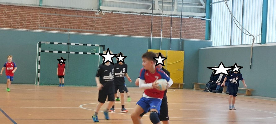 Jugendhandballspiel der HSG Coswig in einer Halle. Ein Spieler in Rot-Blau mit Ball im Fokus, andere Spieler in Bewegung.